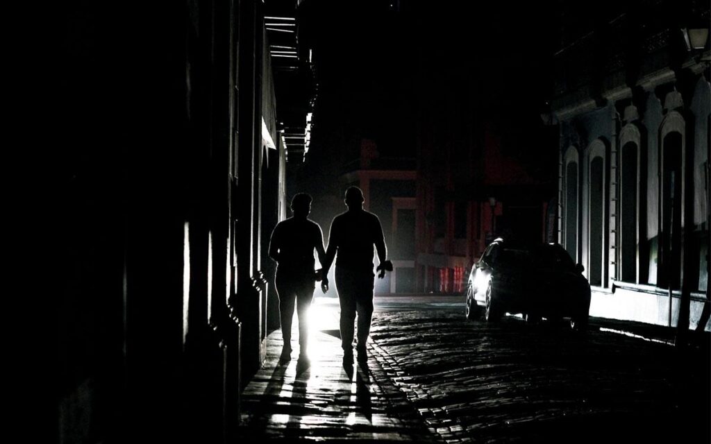 People walk through San Juan during a power outage.