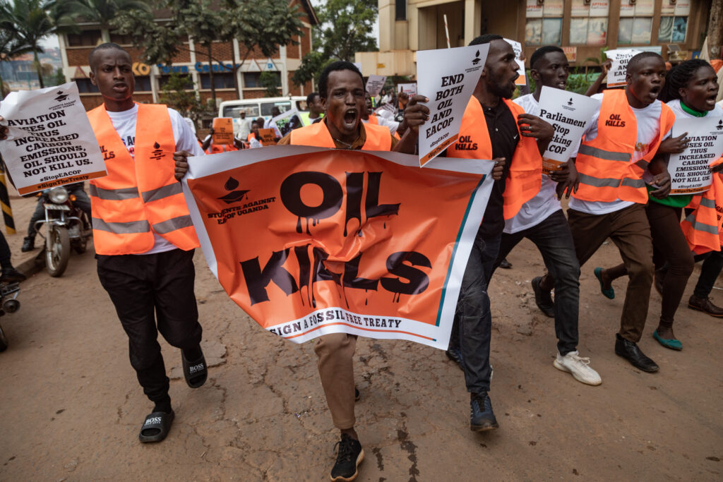 Environmental activists hold banners and chant slogans as they protest against the East African Crude Oil Pipeline Project on Aug. 26 in Kampala, Ugandan. Credit: Badru Katumba/AFP via Getty Images