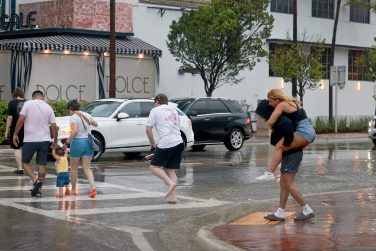 People make their way through heavy rain as streets begin to flood on June 12 in Miami Beach. The plaintiffs are all residents of the jurisdiction that the complaint points out is uniquely vulnerable to hotter temperatures, rising seas and more damaging storms. Credit: Joe Raedle/Getty Images