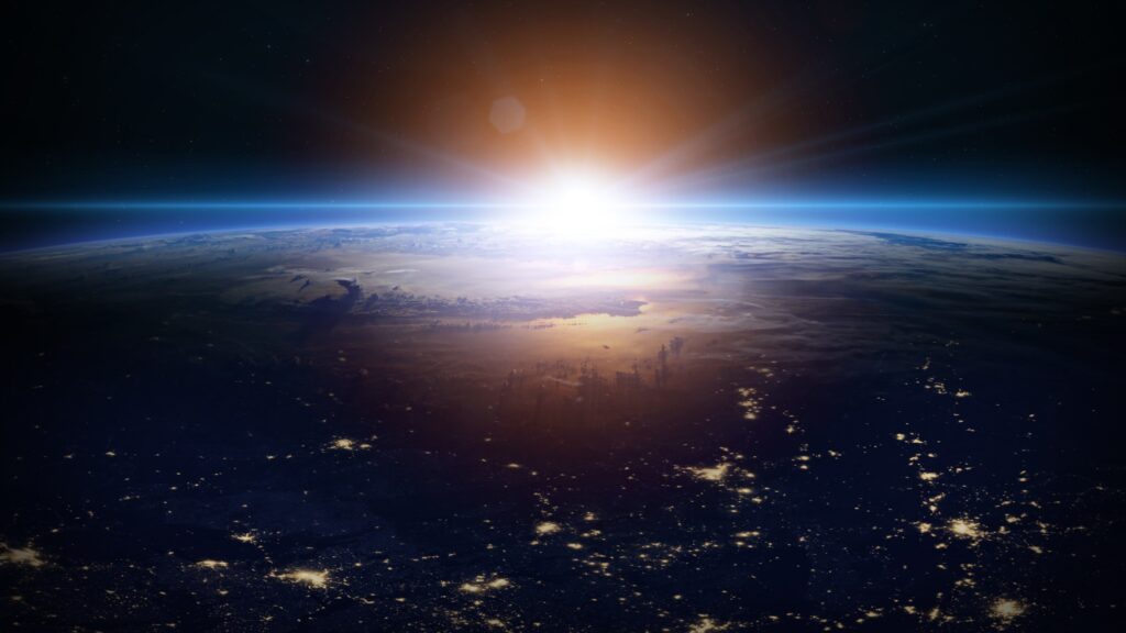 view of Earth from space with the sun rising in the distance