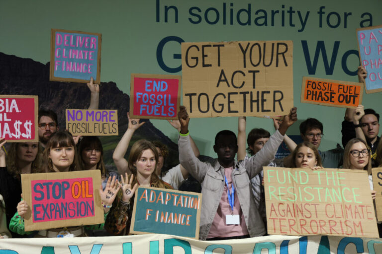 People, many of them young, hold signs with messages like