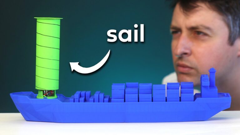 Blue plastic ship model with a tall neon green cylindrical sail; a man looks on in the background.